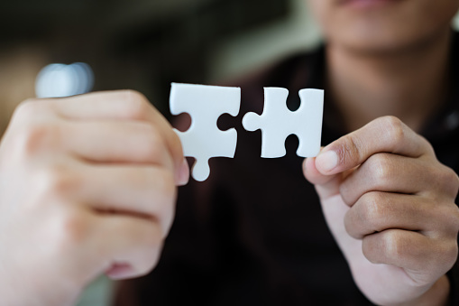 Two people holding a puzzle piece together. Concept of teamwork and collaboration. Scene is positive and uplifting, as it shows two people working together to solve a problem