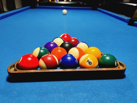 Close up shot of pool sport balls in a rack on a blue pool table at a sport bar during a tournament. There are no recognizable persons or trademarks in the shot.