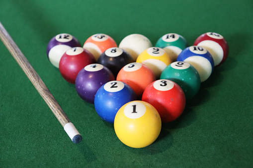 Creative photography of colourful billiard balls and cue stick.