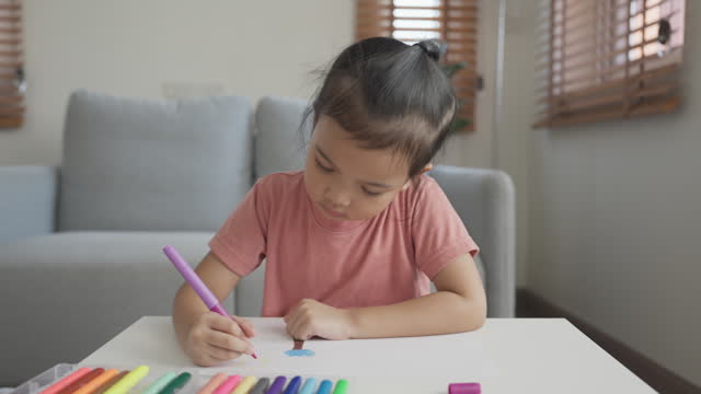 Asian little girl enjoys drawing and coloring using felt tip pen
