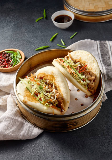 istock Savory Bao buns stuffed with pulled pork and fresh vegetables, captured from above on a dark background 2142295576