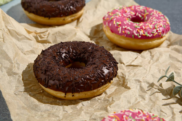 istock Assorted donuts with colorful glazes and sprinkles, presented on rustic parchment paper for a casual sweet treat 2142295593