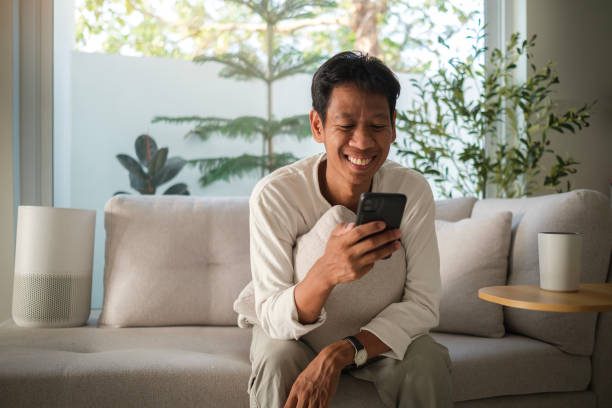 istock Happy relaxed man sitting on couch at cozy home and using mobile phone. 2142332240