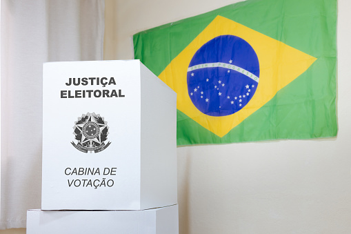 Showcasing a voting booth featuring the Brazilian electronic voting machine, set against a backdrop adorned with the Brazilian flag. This image epitomizes democracy and the electoral process in Brazil, symbolized by the voting booth