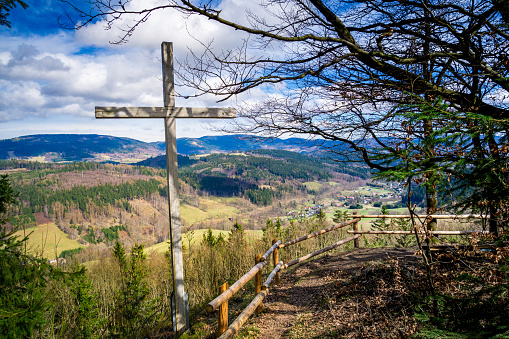 Wooden Cross on Top of Hill with view on town in a valley