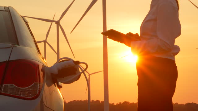 EV charging station Technology Sustainability with Wind turbines energy at sunset