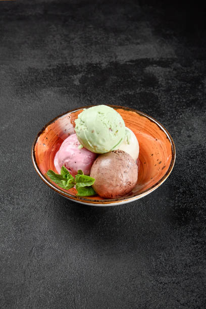 istock Assorted ice cream in ceramic bowl on black concrete background. Balls ice cream in minimal style. Assorted taste of ice cream: chocolate, strawberry, pistachio, vanilla. 2142442492