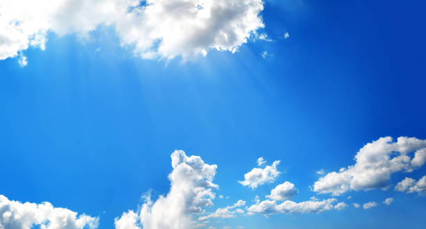 Empty blue sunny sky with shinning sun and white clouds background