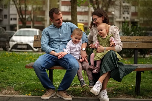 Family with two children sitting on a bench in the park