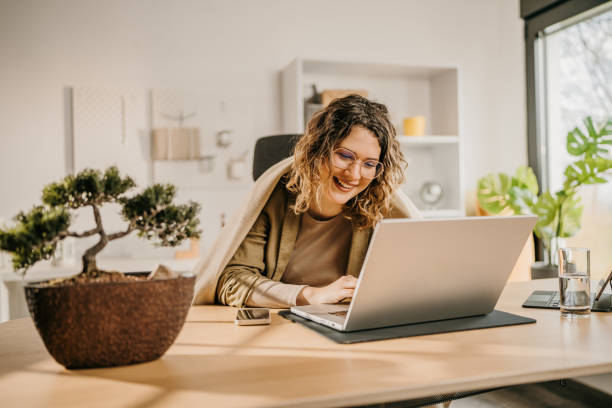 istock Cheerful young woman using laptop at home 2142483943