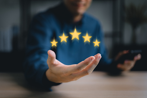 giving a five star rating. hand of customer or client holding the stars to complete five stars. with copy space. Service rating, satisfaction concept.