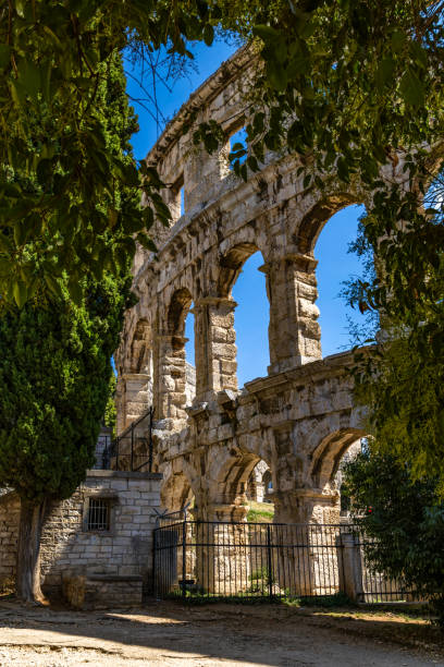 Pula Arena in Istria, Croatia, one of the best preserved Roman amphitheatres. This shows one of the radial passages with stairs on the second story of the seating area or cavea. Dating from the 1st century CE and built during the reign of Emperor Vespasian, it is an ancient Roman elliptical amphitheatre constructed of local limestone ashlar masonry without mortar. The exterior of this iconic landmark features 2 tiers of arched openings or arcades, the lower of which is seen in the background