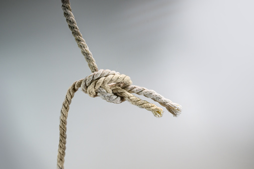 Two ropes are tied together in a knot, business concept for teamwork and cooperation, gray background, copy space, selected focus