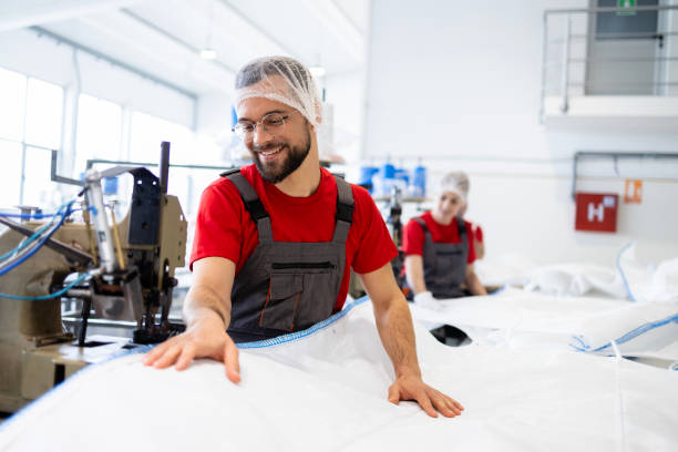 istock Portrait of professional tailor standing by sewing machine inside textile factory. 2142665498