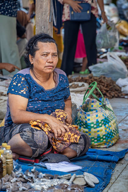 Bukit Lawang, Sumatra, Indonesia - January 21th 2024:  Female greengrocer sitting on the floor in her marked stall at a large village marked on the Indonesian island Sumatra