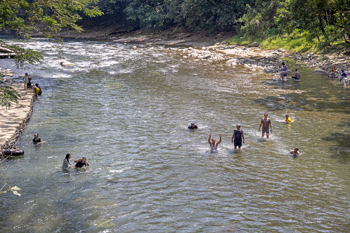 Bukit Lawang, Sumatra, Indonesia - January 21th 2024:  People having fun bathing in a river on a hot tropical day