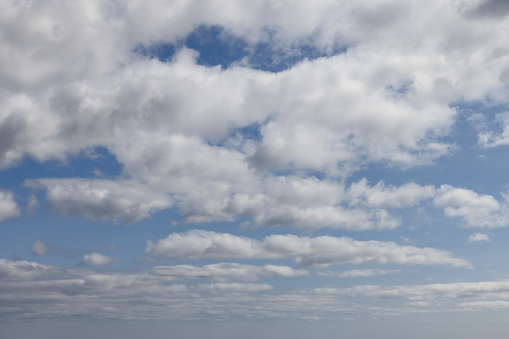 Expansive view of a serene sky, dotted with fluffy cumulus clouds against a vibrant blue backdrop, ideal for sky replacement in creative projects