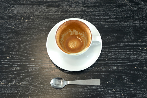 Coffee depression, empty coffee cup after drink with coffee stain of espresso on table. Cup of Espresso on a wooden table. Close up hot coffee Espresso in a white mug on red table background. Flat-lay, top view. Cup of coffee with pure black and brown. Copy space, food and drink concept.