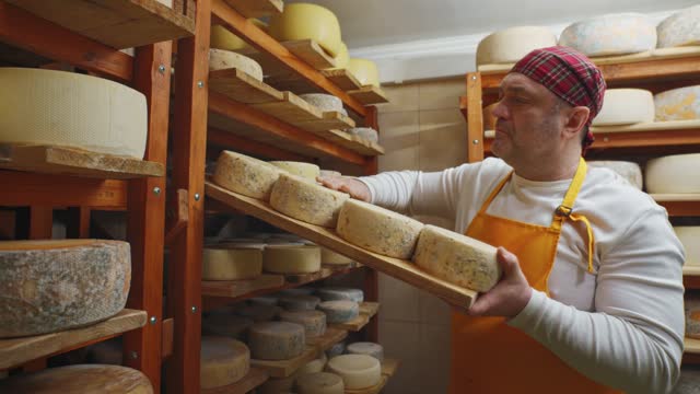 Cheesemaker turns the wheels of the cheese over for further ripening