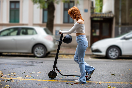 young woman pushing e-scooter in the city