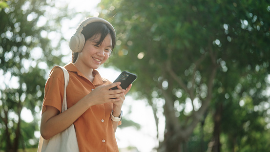 Asian teenage girl using smartphone at green environment.