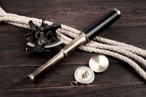 vintage naval spyglass telescope with sextant and compass on wooden background