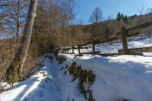 Hiking path besides a fence in a snowy winter landscape in the Alps, Barcis