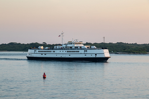 A ferry leaving the harbor of Woods Hole on Cape Cod on a trip to Marthas Vineyard at sunset