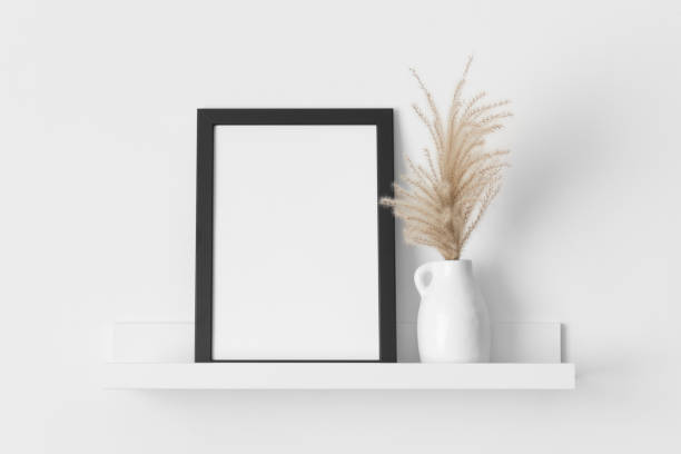 istock Black frame mockup with a pampas decoration on the wall shelf. 2143138743