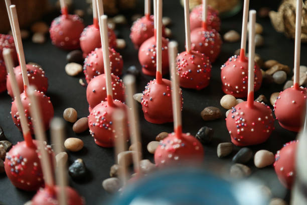A table filled with various types of red candy, such as lollipops, gummy bears, and jelly beans, all covered in colorful sprinkles.