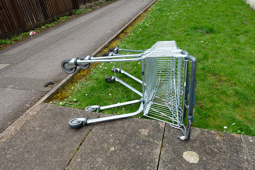 A Abandoned Shopping Trolleys on a Grass Verge in a Town on their Side Next To A Path