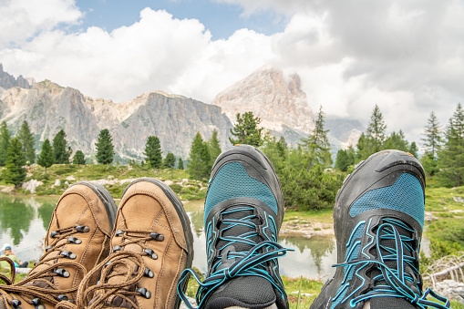 close-up of bleu and brown hiking boots with lago di Limides lake and Tofana di Rozes mountain in the background. Hiking theme in the Italian Dolomites. Beautiful hiking spot for active tourists.