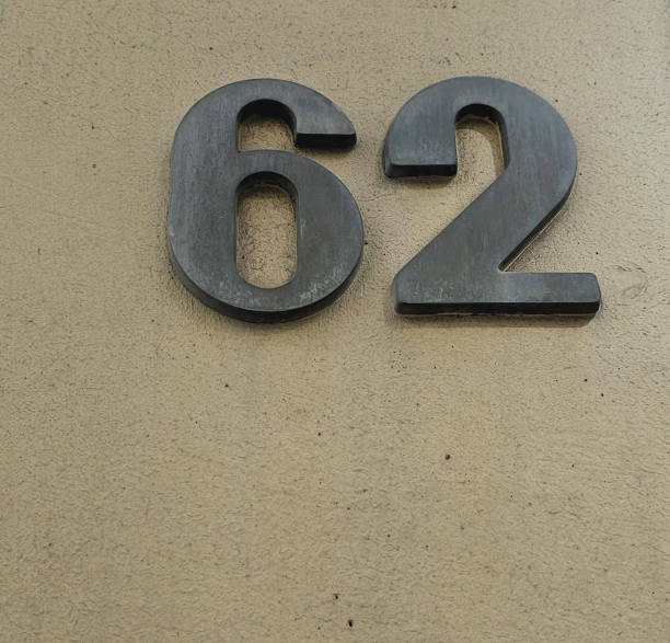 istock Old shabby numbers sixty two, or 62. Uneven surface in the background 2143223809