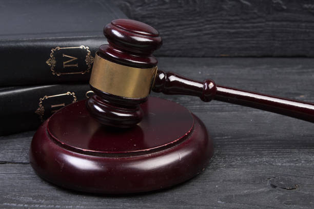 law concept - open law book with a wooden judges gavel on table in a courtroom or law enforcement office isolated on white background. copy space for text. - justice entertainment group stock-fotos und bilder