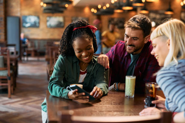 istock Young happy friends using smart phone in a pub. 2143277100