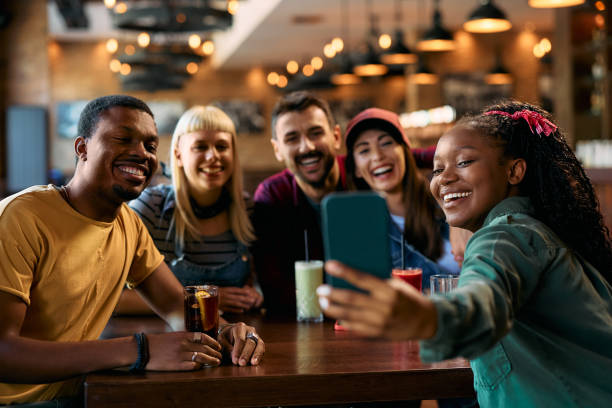 istock Multiracial group of happy friends taking selfie in a pub. 2143277107