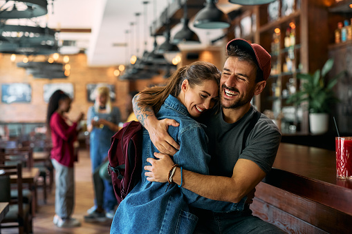 Cheerful man and his girlfriend embracing in a bar. Copy space.