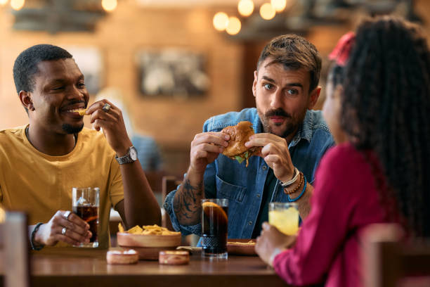 istock Young friends enjoying while eating and talking in a pub. 2143282946