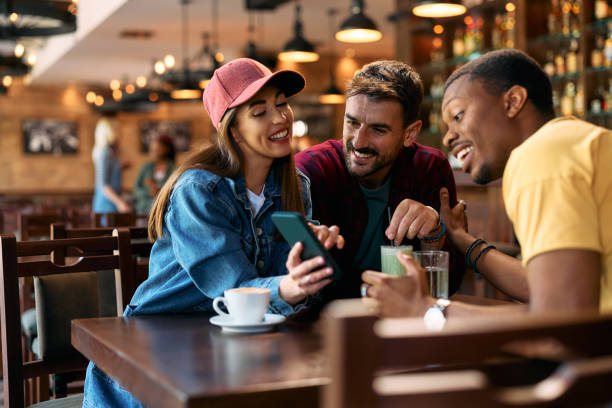 istock Group of happy friends using cell phone in a pub. 2143283483