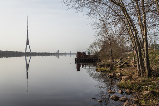 The bank of the Daugava River in spring near the Kengarags residential area. In the background is the island of Zakusala with a television tower