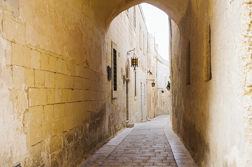 City center od Mdina. Yellow color building walls. Arch alley cityscape.