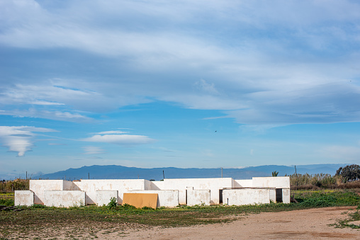 White cubic houses with blue shutters under a cloudy sky in Almeria's countryside.