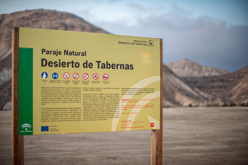 Sign at the entrance of Tabernas Desert Natural Park in Almería, Spain with mountains in the background.