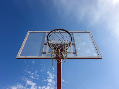 Basketball hoop with net from below on an outdoor court with sky background