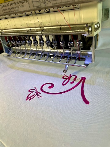 machine embroidery of a logo on a T-shirt with purple threads