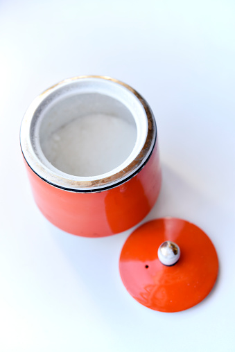 Red ceramic sugar bowl on a white background. Sugar in a jar.