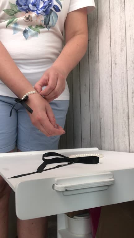 The woman makes a review of the purchase. A necklace and white pearl bracelet with black bows. Demonstrates the necklace. Vertical video.