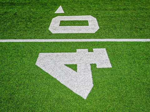 Bright green turf football field surface with white yard line markings. Focus on the forty yard line marker. Overhead view.