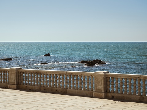 View of the seaside beach promenade of Cadiz with rock formations in the water during a summer vacation, sea view, blue horizon, sunshine