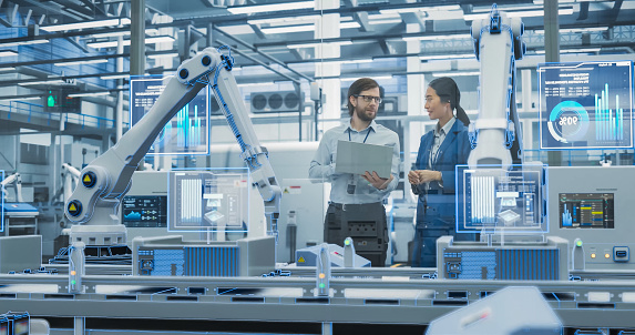 Electronics Factory Assembly Line Digitalization: Automated Robot Arms Manufacturing Equipment. Managers Discussing Work while Futuristic AI Computer Vision Analyzing, Scanning Conveyor Line